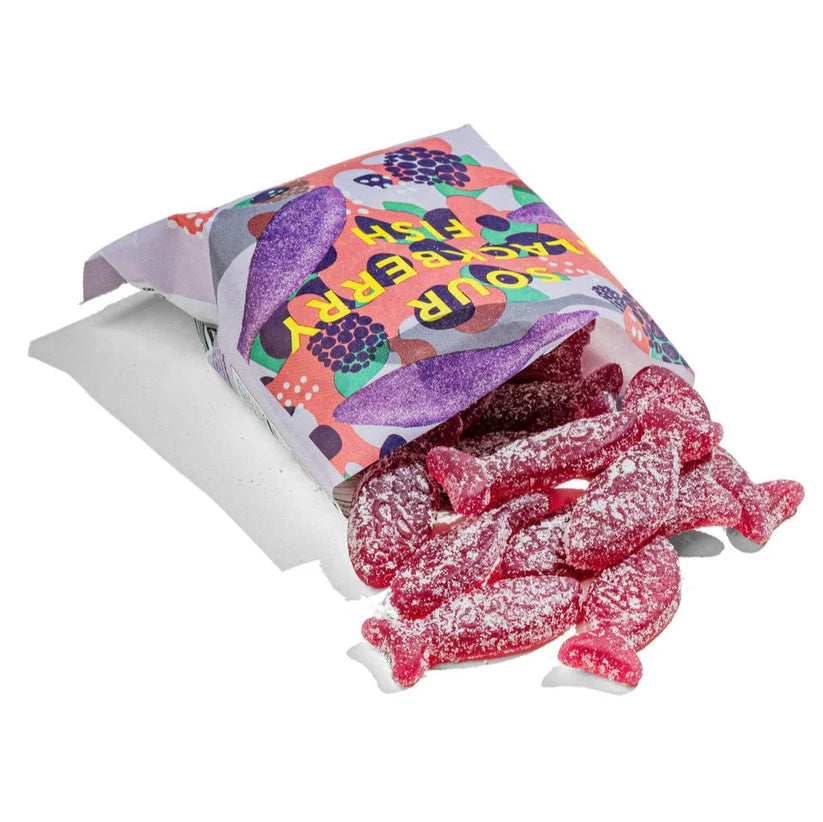 Colorful bag of sour blackberry fish-shaped swedish candies, spilling out onto a white surface