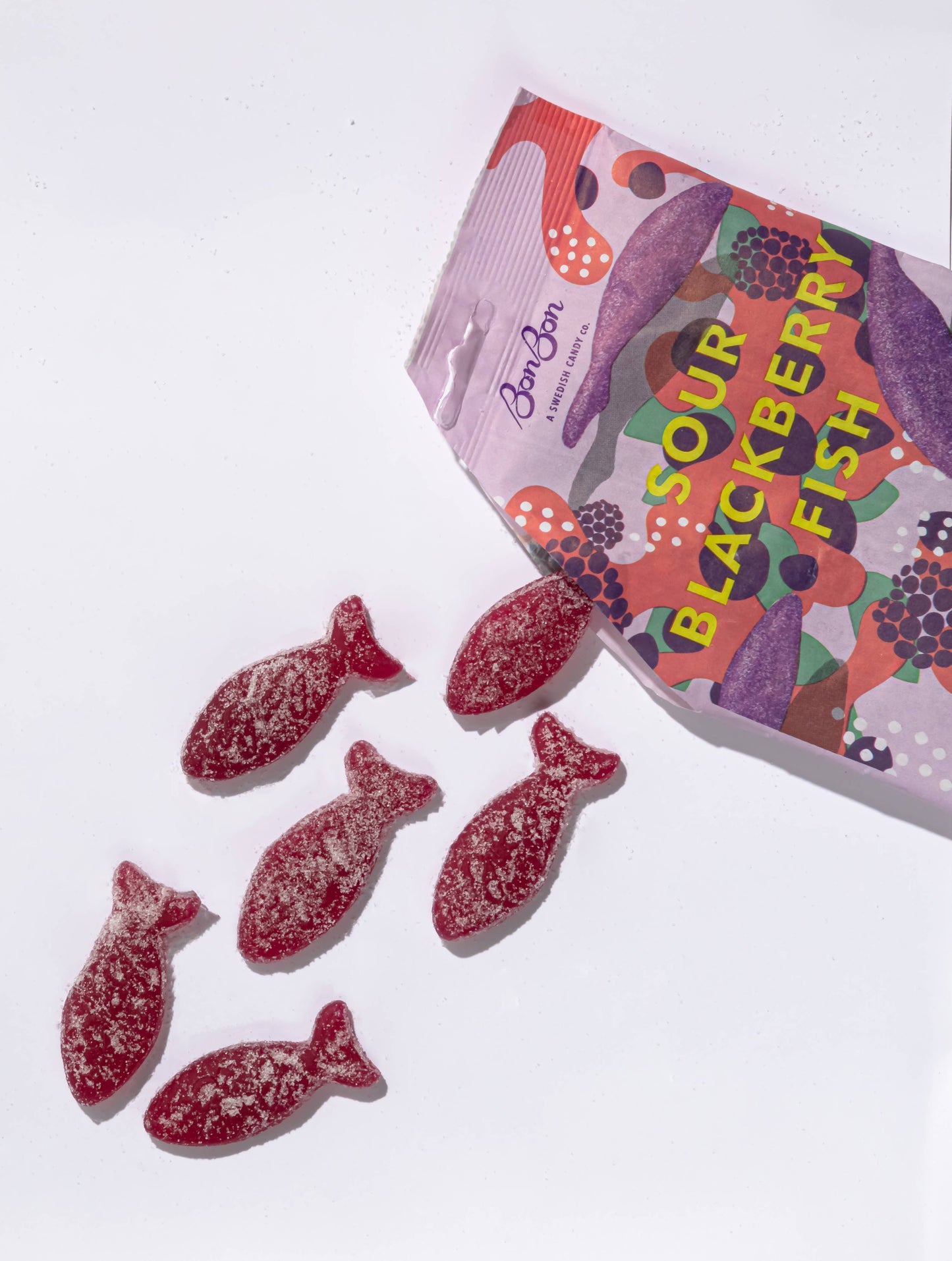 Sour blackberry fish candies with a colorful packaging on a white background