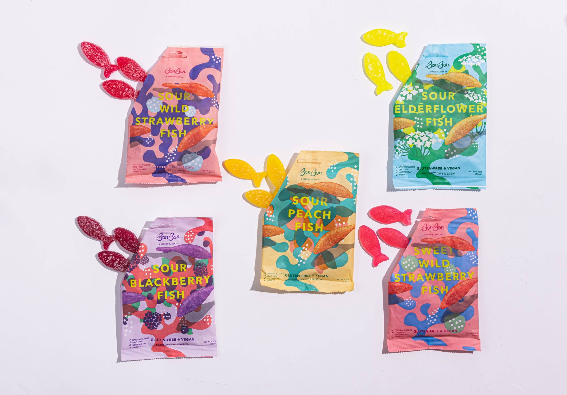 Colorful packages of sweet or sour fish-shaped swedish candies on a white background