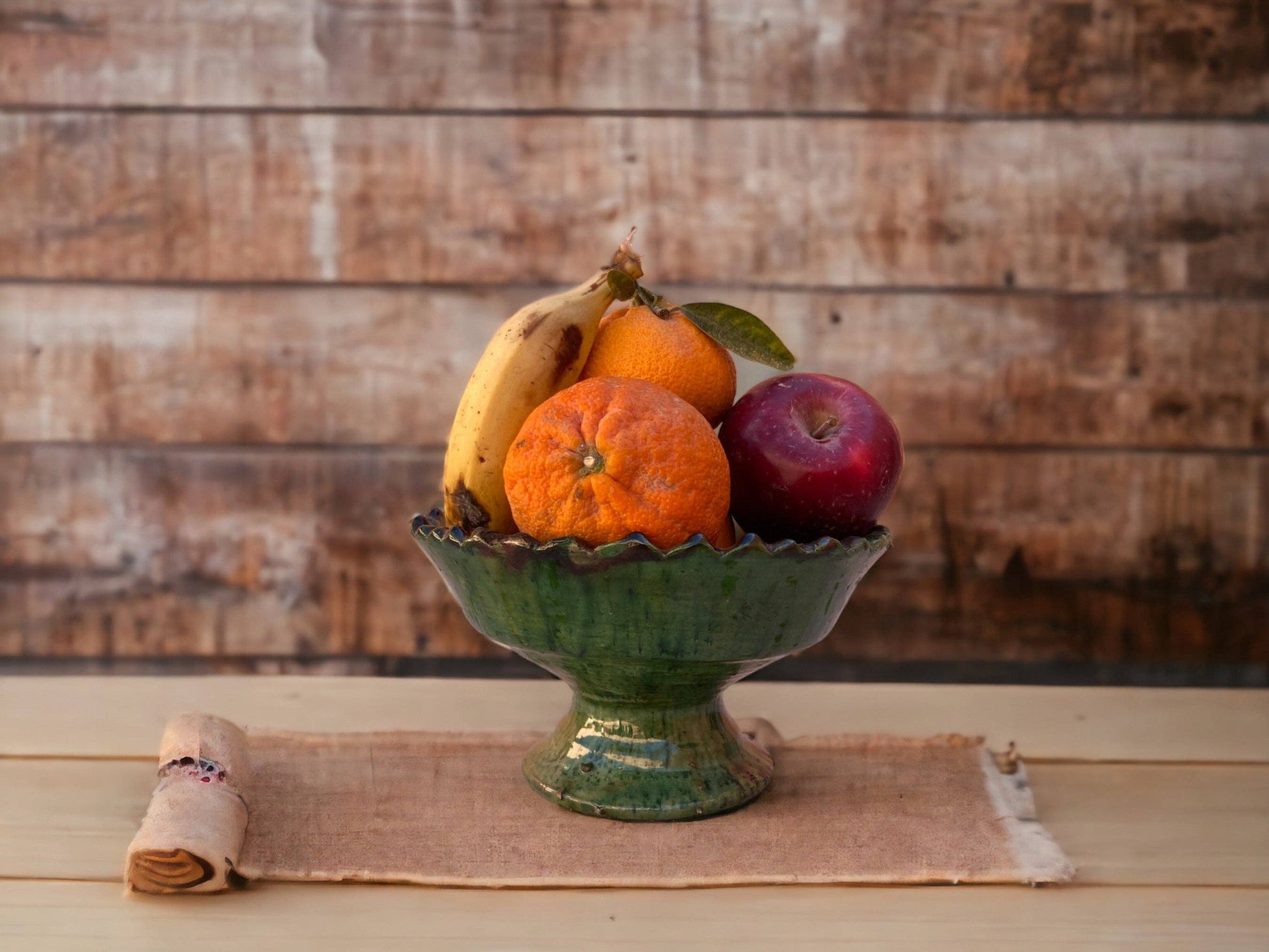 A ceramic fruit bowl with green glaze handmade in Tamegroute, Morocco, containing fruits.
