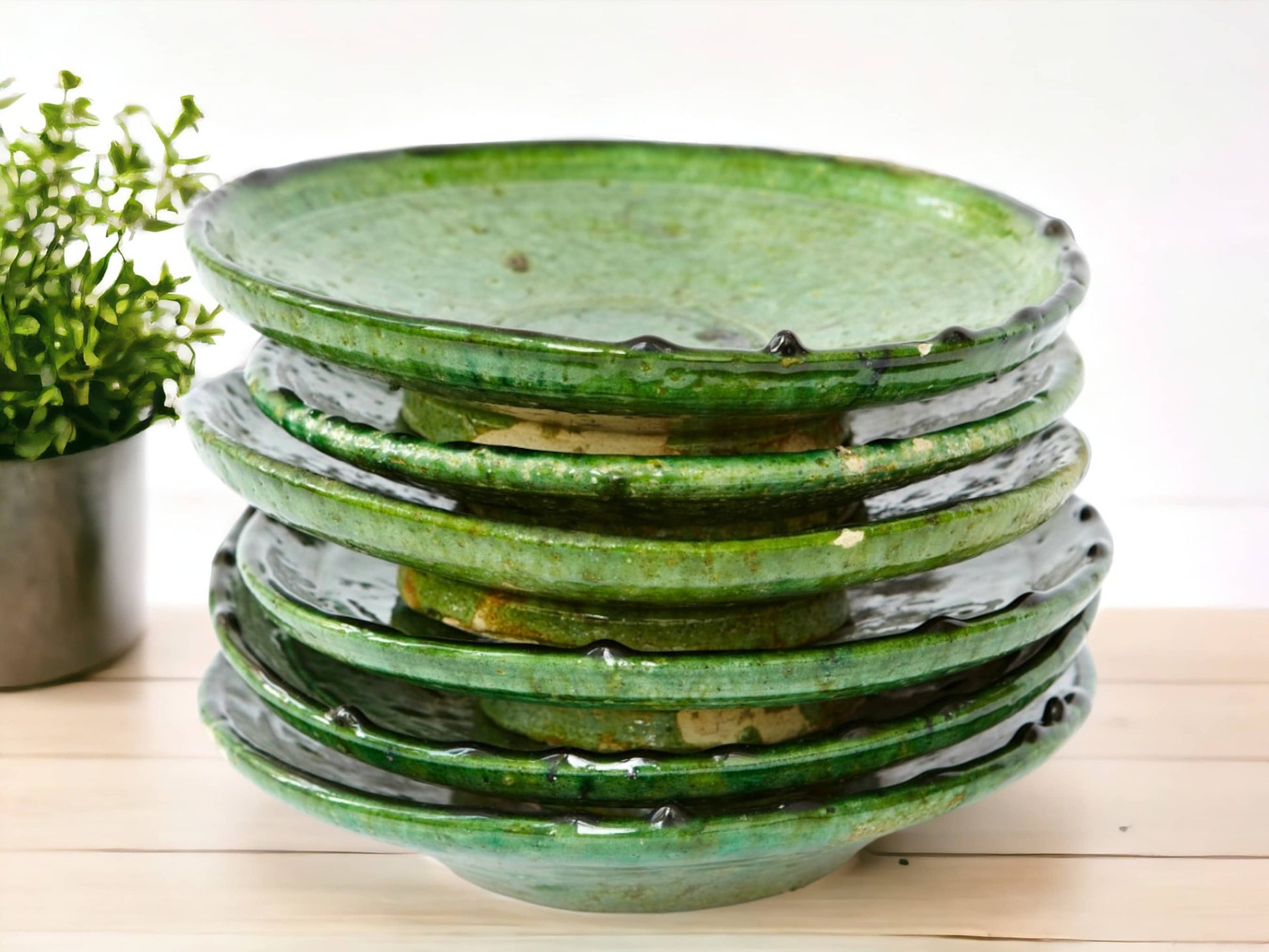 A stack of green glazed ceramic plates with varying shades and textures, indicative of handmade tamegroute moroccan pottery.