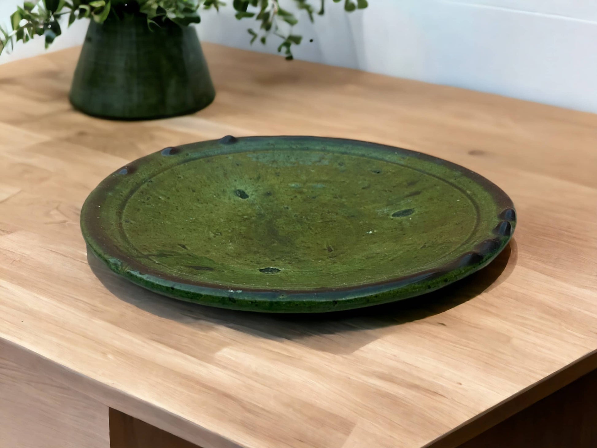 A green glazed ceramic plate with varying shades and textures, indicative of handmade tamegroute moroccan pottery.