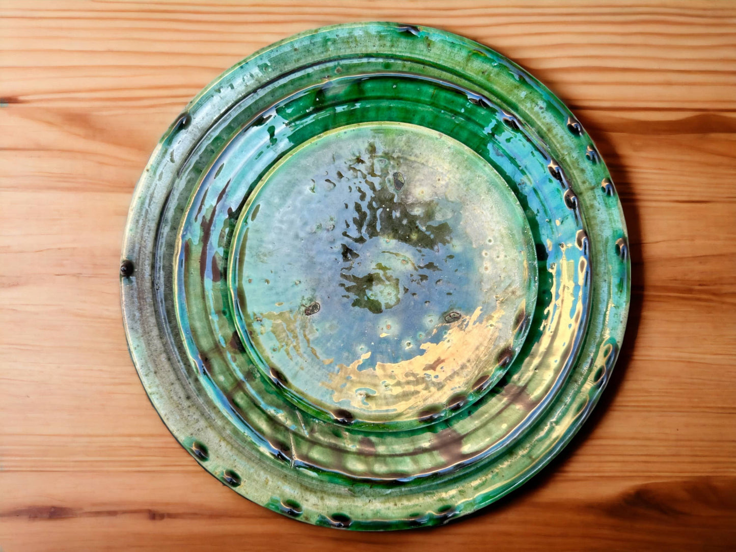 A stack of green glazed ceramic plates with varying shades and textures, indicative of handmade tamegroute moroccan pottery.