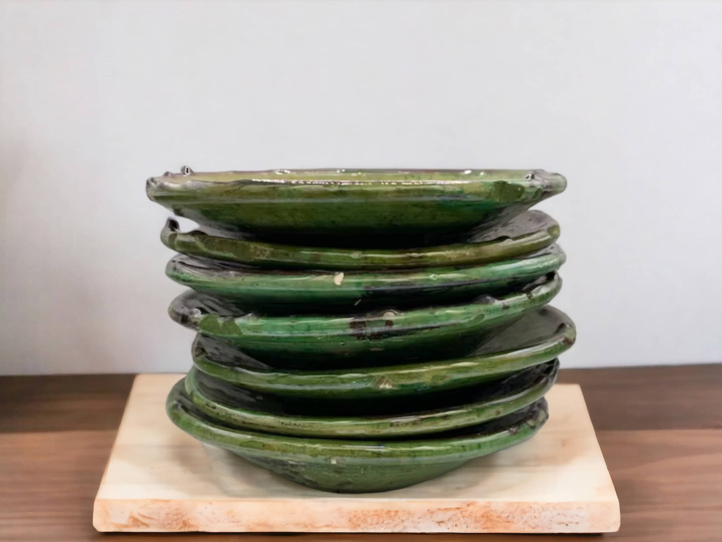 A stack of green glazed ceramic plates with varying shades and textures, indicative of handmade tamegroute moroccan pottery, viewed from the side.