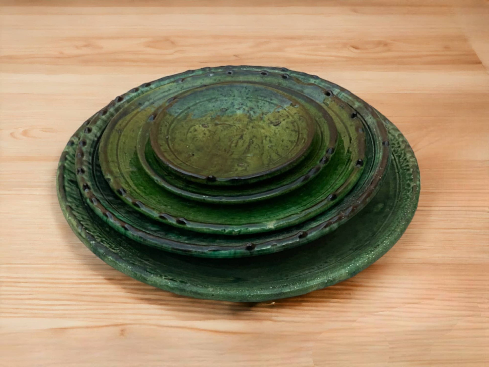 A stack of green glazed ceramic plates with varying shades and textures, indicative of handmade tamegroute moroccan pottery.