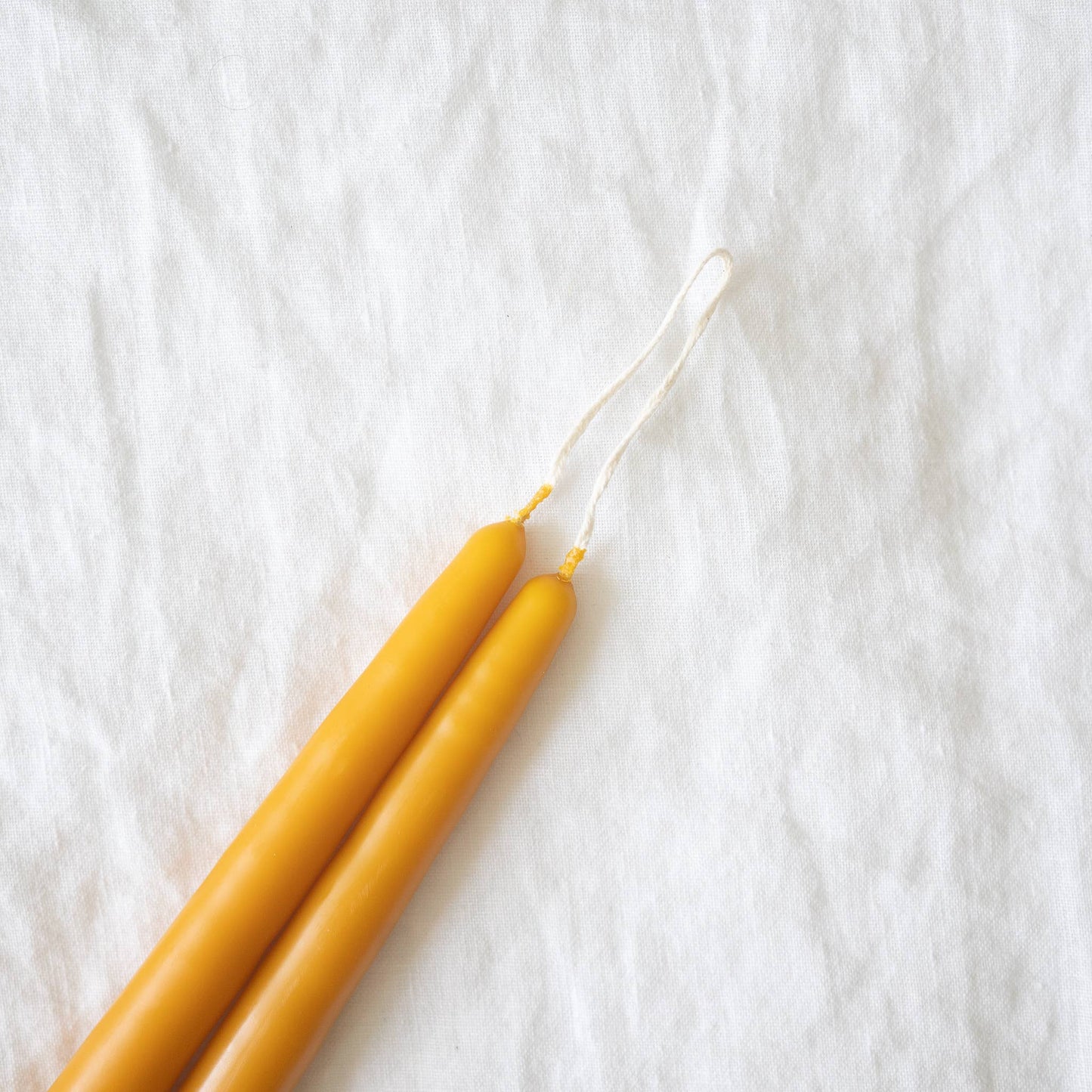 Close-up on a pair of hand-dipped harvest gold taper candles