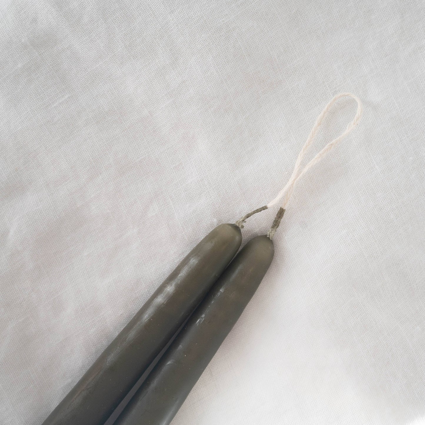 Close-up on a pair of hand-dipped olive taper candles.