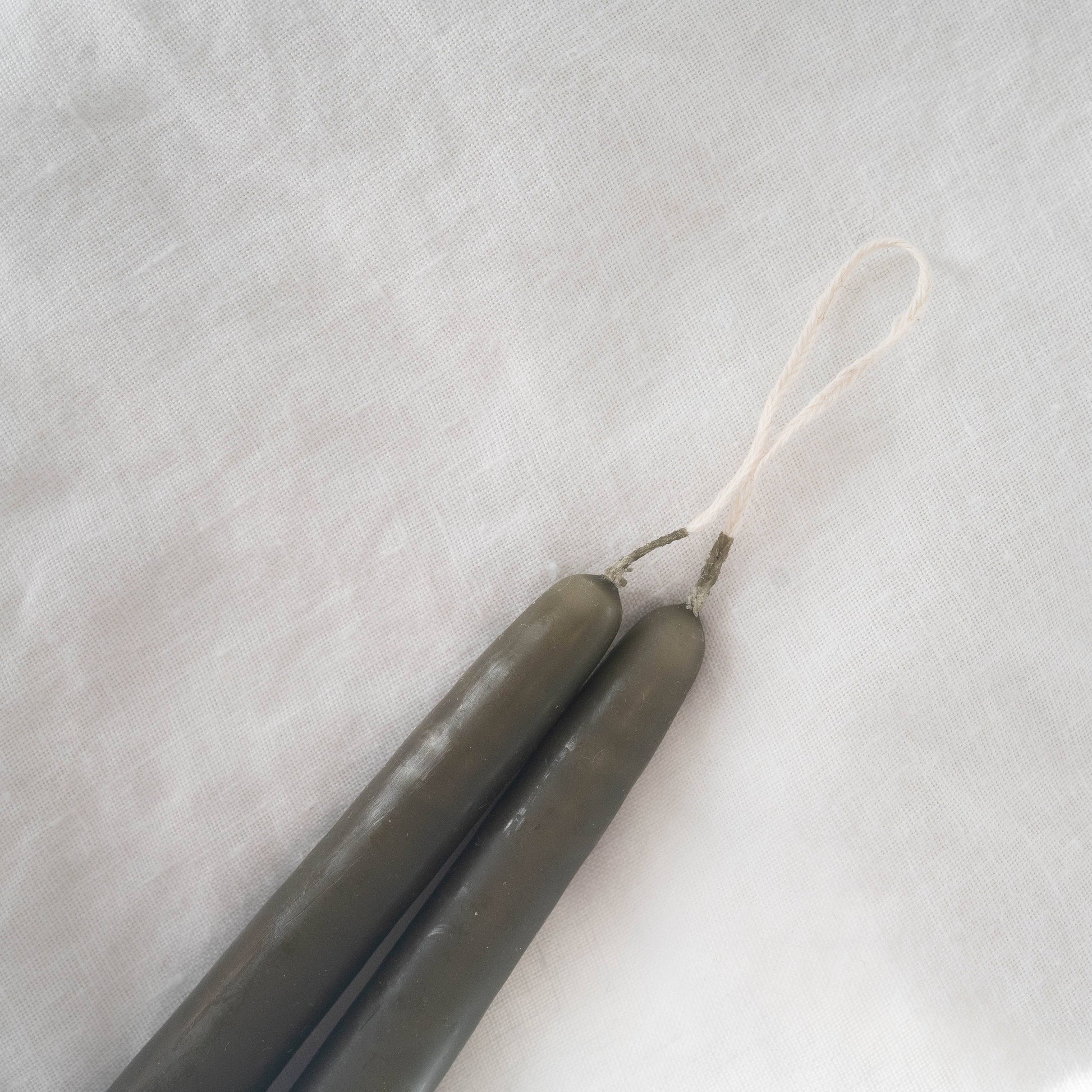 Close-up on a pair of hand-dipped olive taper candles.
