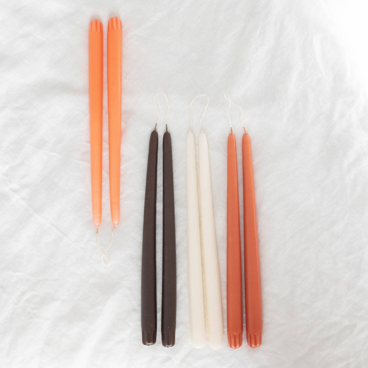 Hand-dipped taper candles pairs in various colors: ivory, brown, orange and terracotta.