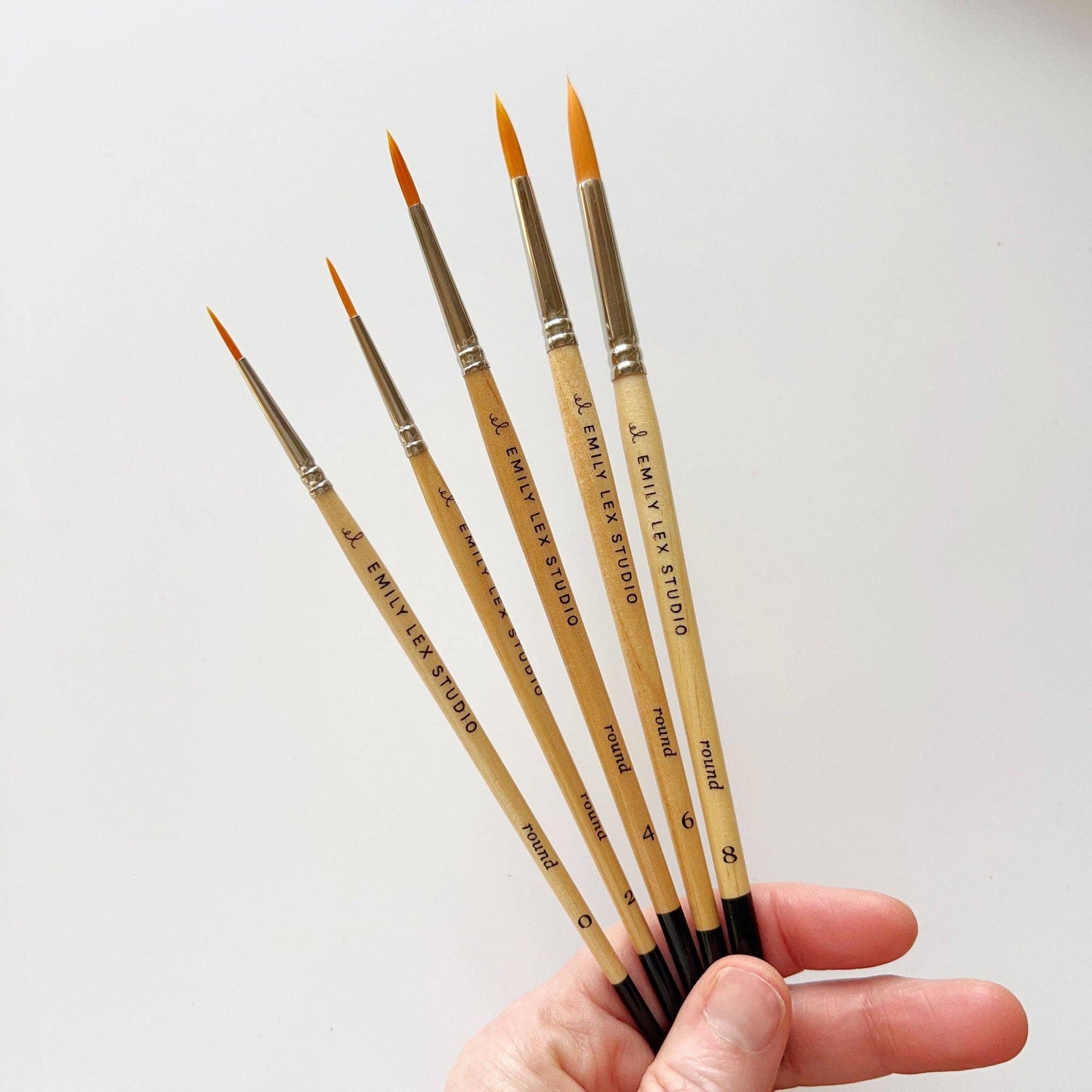 A set of five watercolor paintbrushes with golden synthetic taklon bristles, seamless aluminum ferrules, and lacquered wood handles, from emily lex studio.