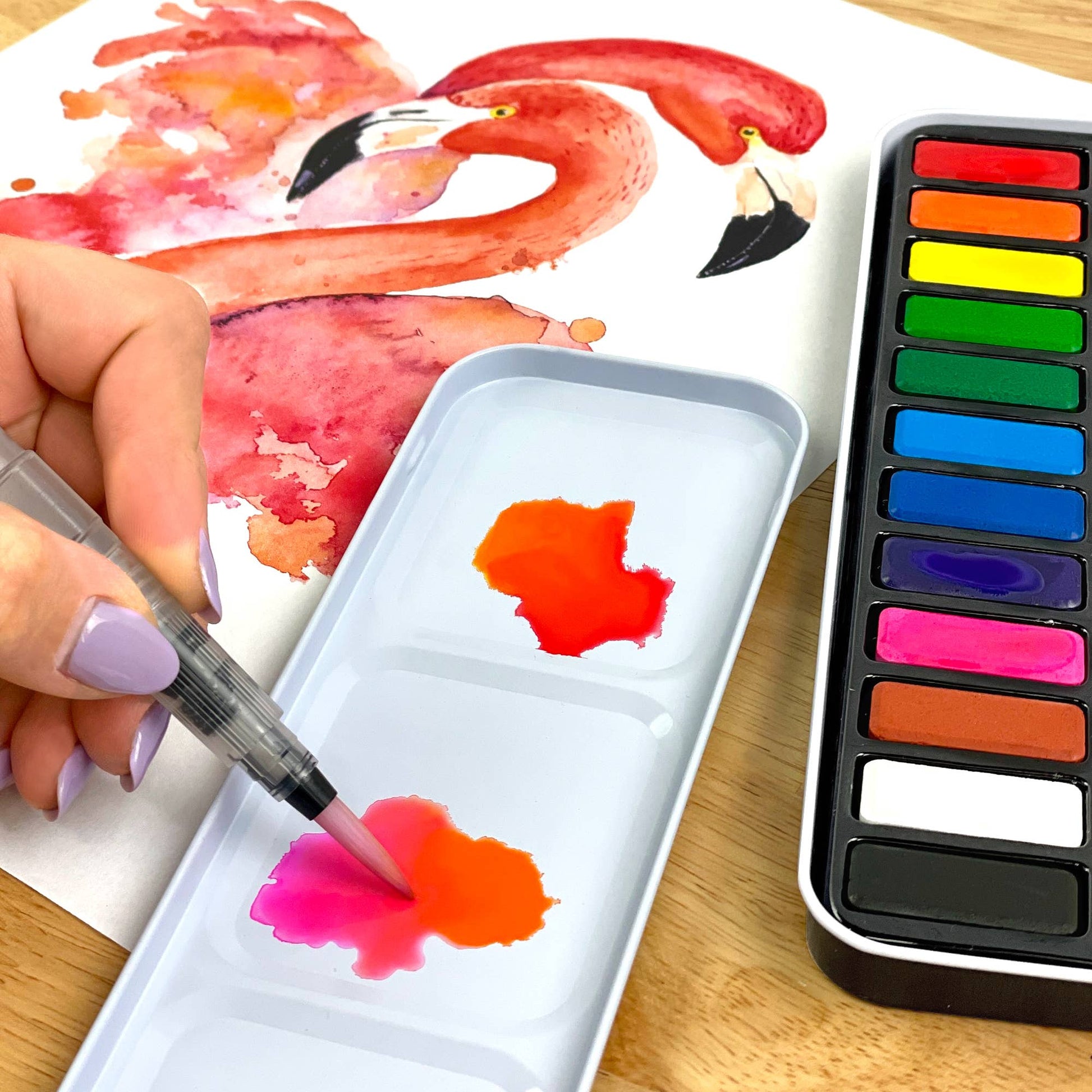 Person painting a flamingo with watercolors on a wooden table