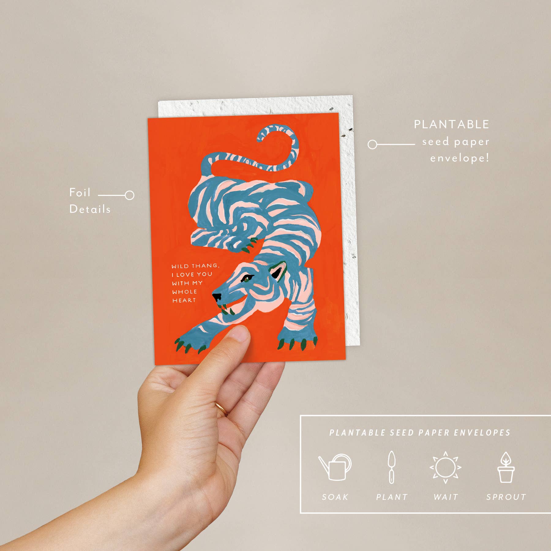 Hand holding a plantable seed paper envelope and a card with a tiger design on an orange background.